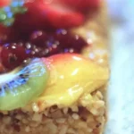 Obstkuchen mit Vanillesoße und gehackten Haselnüssen