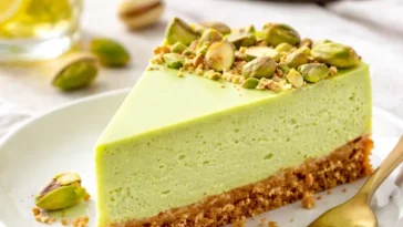 Leckerer Pistazien-Käsekuchen auf einem Teller, dekoriert mit Pistazien.