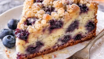 Blaubeer-Muffins mit Streusel-Topping auf einem rustikalen Holzbrett.