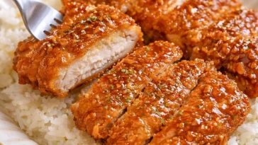 Honig-Knoblauch-Crispy-Hühnchen in einer knusprigen Panade, serviert mit Beilagen.