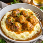 Saftige Fleischbällchen in cremiger Sauce mit Kartoffelpüree serviert.