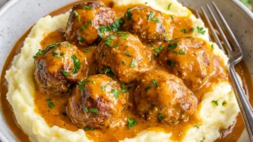 Saftige Fleischbällchen in cremiger Sauce mit Kartoffelpüree serviert.