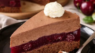 Kirschtorte mit Schokocreme dekoriert mit Kirschen und Schokoladensplittern.