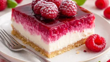 Cremiger Himbeer-Käsekuchen auf einem Teller dekoriert mit frischen Himbeeren