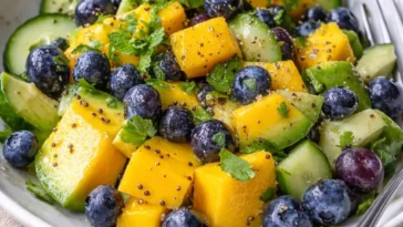 Mango Gurkensalat mit Heidelbeeren und Avocado auf einem dekorativen Teller