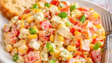 Paprika-Mais-Salat mit Feta und Joghurt auf einem Teller serviert