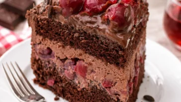 Schokotorte mit Kirschen und Schokobiskuit auf einem eleganten Dessertteller.