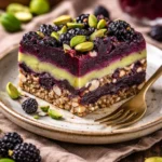 Schwarze Johannisbeer-Pistazien-Traumriegel auf einem Holztablett