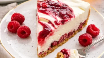 Delikater White Chocolate Raspberry Cheesecake mit frischen Himbeeren und Schokoladensauce