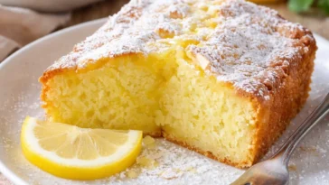 Leckerer Zitronenkuchen auf einem Teller mit frischen Zitronen