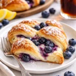 Blaubeer-Cremekäse-Teigzopf frisch gebacken auf einem Holzbrett