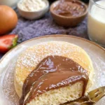 Fluffige Pancakes in einer Pfanne gebacken, serviert mit frischem Obst.
