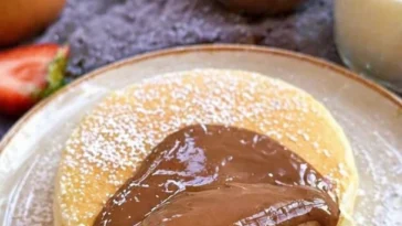 Fluffige Pancakes in einer Pfanne gebacken, serviert mit frischem Obst.