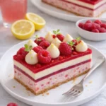Himbeer-Zitronen-Käsekuchen mit frischen Himbeeren und Zitrone auf einem weißen Teller.