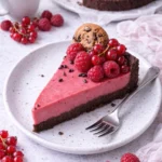Himbeermousse-Schoko-Cookie-Tarte auf einem Teller serviert, dekoriert mit frischen Himbeeren.