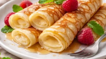 Hüttenkäse-Pfannkuchen auf einem Teller, garniert mit frischen Früchten