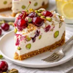 Kirschen-Pistazien-Käsekuchen auf einem Teller mit frischen Kirschen.