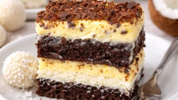 Kokos-Creme-Kuchen mit RAFFAELLO auf einem Teller, dekoriert mit Kokosraspeln