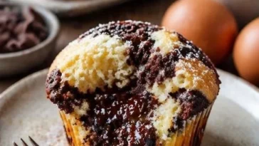Marmorierte Muffins aus Schokolade und Vanille auf einem rustikalen Holzbrett