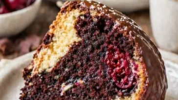 Marmorkuchen mit Kirschen und Schokoladenguss auf einem weißen Teller