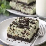 Minz-Oreo-Cheesecake-Riegel auf einem Teller, dekoriert mit Minzblättern