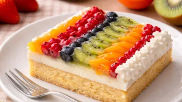 Obstkuchen mit Puddingfüllung auf dem Blech, frisch gebacken und dekoriert.