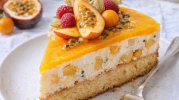 Pfirsich-Maracuja-Torte auf einem Teller, dekoriert mit frischen Früchten.