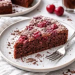 Saftiger Schoko-Kirsch-Kuchen mit Schokolade und Kirschen auf einem Teller