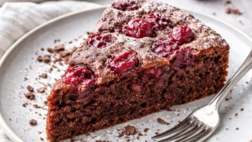 Saftiger Schoko-Kirsch-Kuchen mit Schokolade und Kirschen auf einem Teller
