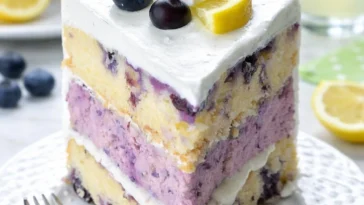 Zitronen-Blaubeer-Käsekuchen auf einem Teller mit frischen Beeren
