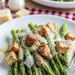 Caesar gegrillter Spargel auf einem Teller, garniert mit Parmesan und Dressing.