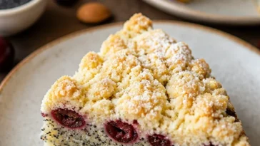Joghurt-Mohn-Kuchen mit Kirschen und Streuseln auf einem Tisch serviert
