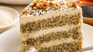Leckere Mohn-Mandel-Torte auf einem Teller mit frischen Mandeln und Mohnsamen.