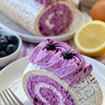 Roulade Pavlova mit Johannisbeeren und Kokos auf einem Teller serviert.