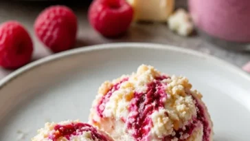 Himbeer-Frischkäse-Bites auf einem Teller dekoriert mit frischen Himbeeren