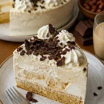 Windbeuteltorte mit Nussboden und Baileys Sahne auf einem eleganten Dessertteller.
