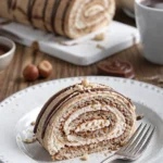 Winterliche Glühwein-Nuss-Biskuitrolle mit Nüssen und Gewürzen dekoriert