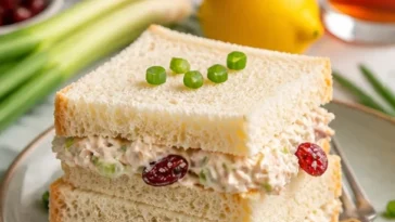 Einfache Hühnersalat-Teesandwiches auf einem Teller präsentiert