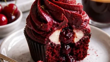 Luxuriöse Samt-Cupcakes mit Sauerkirschkompott auf einem weißen Teller