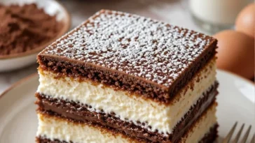 Schichtkuchen mit Biskuit und Milchcreme dekoriert auf einem Teller