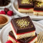 Schoko-Himbeer-Shortbread-Riegel auf einem Teller, dekoriert mit Himbeeren