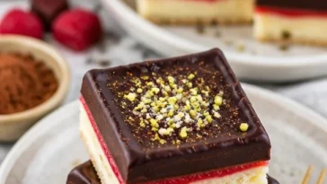 Schoko-Himbeer-Shortbread-Riegel auf einem Teller, dekoriert mit Himbeeren