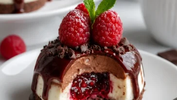 Schokoladen-Himbeer-Cheesecake-Dome mit Himbeersauce und Schokoladendekoration