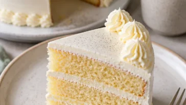 Leckere Vanilletorte auf einem Holzbrett mit frischen Früchten dekoriert.