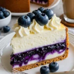Weißer Schokoladen Cheesecake mit Blaubeeren auf einem weißen Teller.
