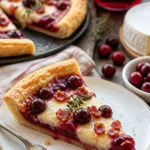 Cranberry-Brie-Tarte mit goldbraunem Teig und frischen Cranberries auf einem Teller