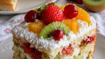 Frischer Obst-Cream-Kuchen mit bunten Früchten und Sahne auf einem Teller