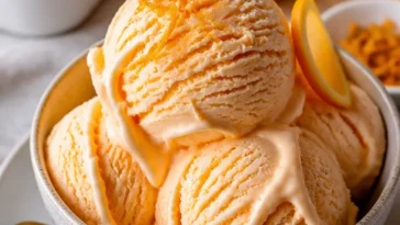 Hausgemachtes Orangen-Eiscreme in einer Waffel mit frischen Orangenstücken