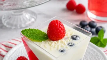 Mini-Desserts Panna Cotta mit Gelee auf einem eleganten Teller serviert.