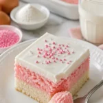 Rosa Vanillekuchenwürfel auf einem Teller, dekoriert mit Sahne